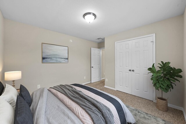 carpeted bedroom featuring baseboards, visible vents, and a closet