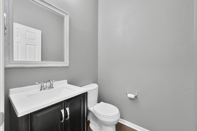 bathroom featuring vanity, baseboards, and toilet
