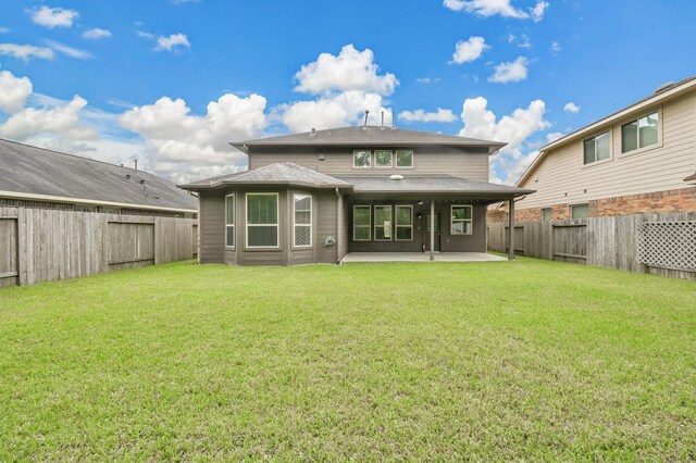 rear view of house featuring a fenced backyard, a patio, and a lawn
