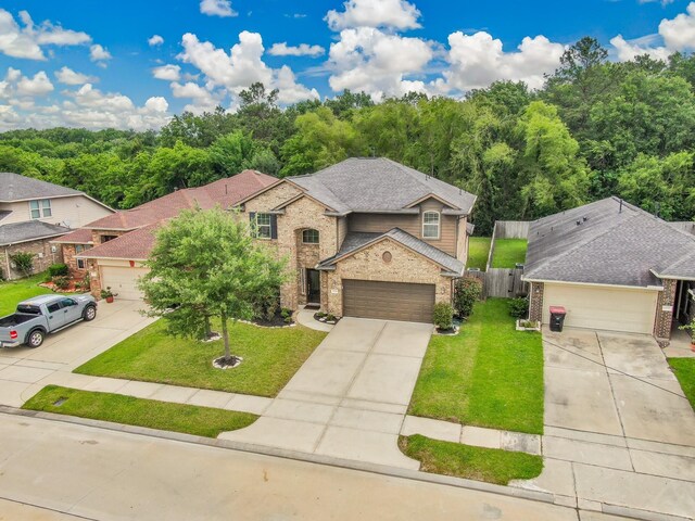 view of front facade featuring brick siding, fence, a front yard, and concrete driveway