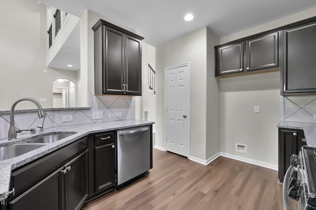 kitchen with dark wood-style flooring, tasteful backsplash, a sink, light stone counters, and stainless steel appliances