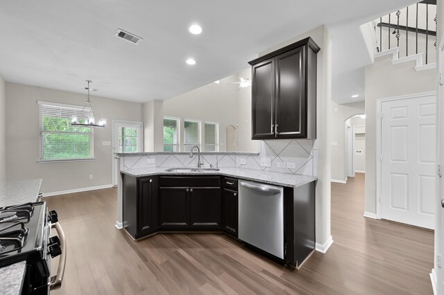 kitchen featuring appliances with stainless steel finishes, a sink, arched walkways, wood finished floors, and tasteful backsplash