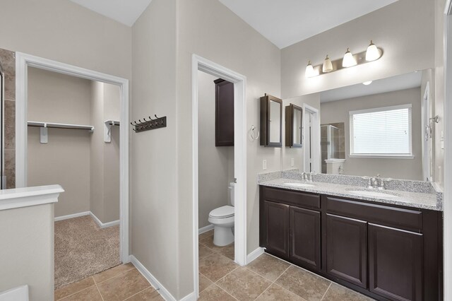 full bath featuring double vanity, a sink, toilet, and a shower stall