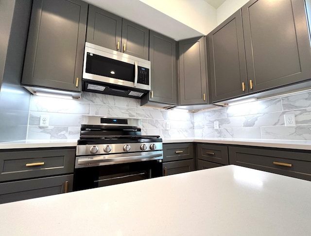 kitchen with light countertops, stainless steel appliances, decorative backsplash, and gray cabinets