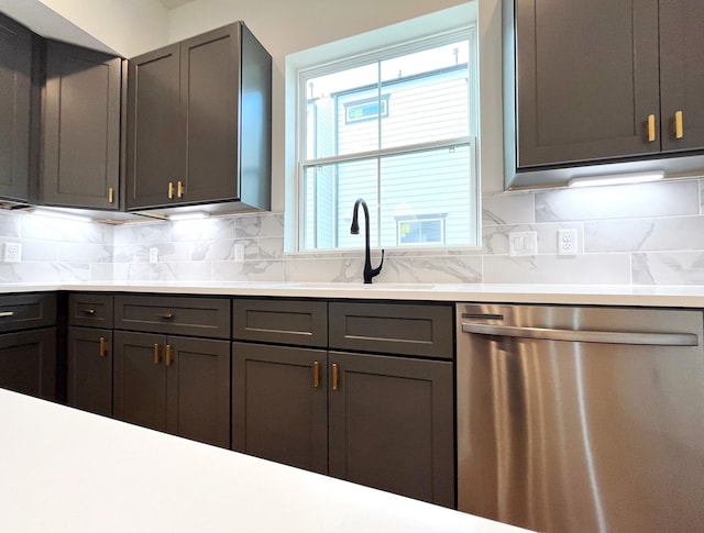 kitchen with stainless steel dishwasher, a sink, decorative backsplash, and light countertops