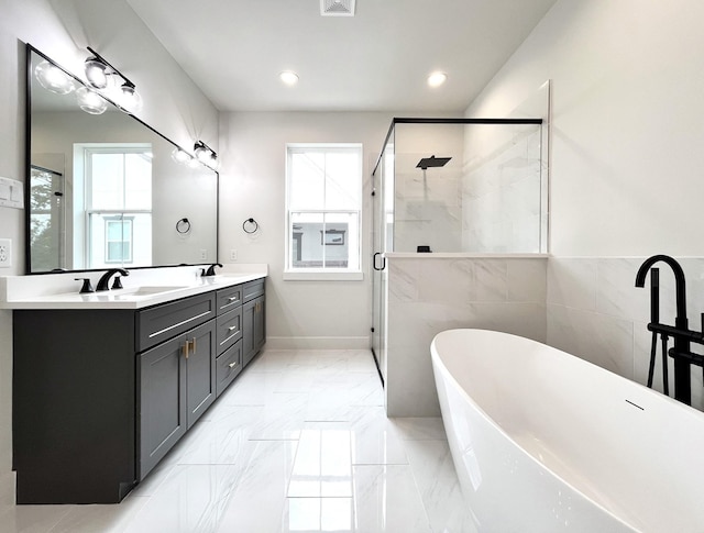 bathroom with double vanity, a shower stall, a sink, a soaking tub, and recessed lighting