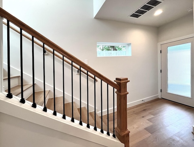 stairway with baseboards, recessed lighting, wood finished floors, and visible vents