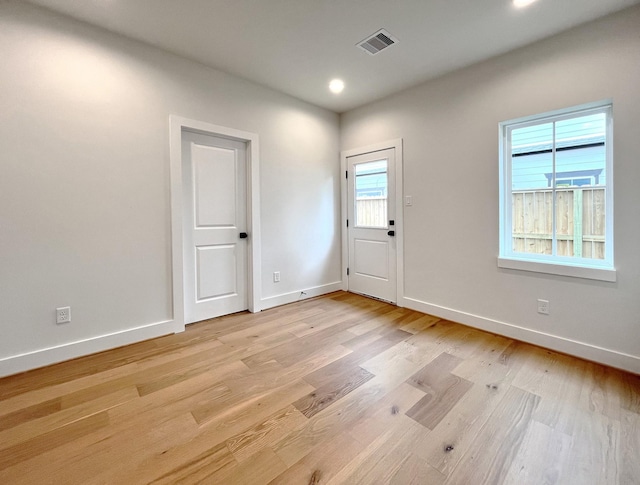 foyer with light wood-style floors, baseboards, and visible vents