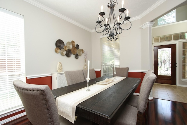 dining space featuring crown molding, a notable chandelier, baseboards, decorative columns, and wood finished floors
