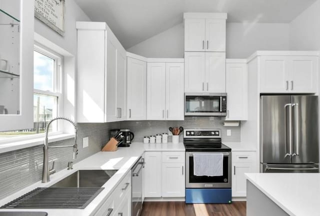 22814 Camino St, Galveston, TX 77554 - kitchen with a sink, lofted ceiling, white cabinets, and stainless steel appliances