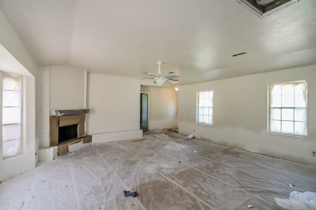 unfurnished living room with a brick fireplace, vaulted ceiling, and visible vents
