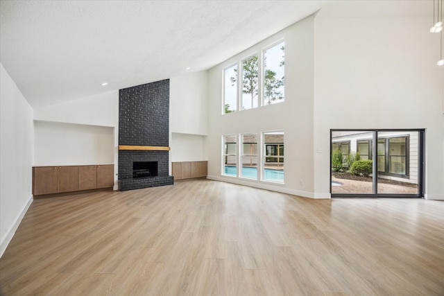 unfurnished living room featuring light wood-style floors, baseboards, a brick fireplace, and high vaulted ceiling