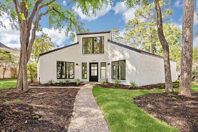 mid-century modern home featuring a front yard and brick siding