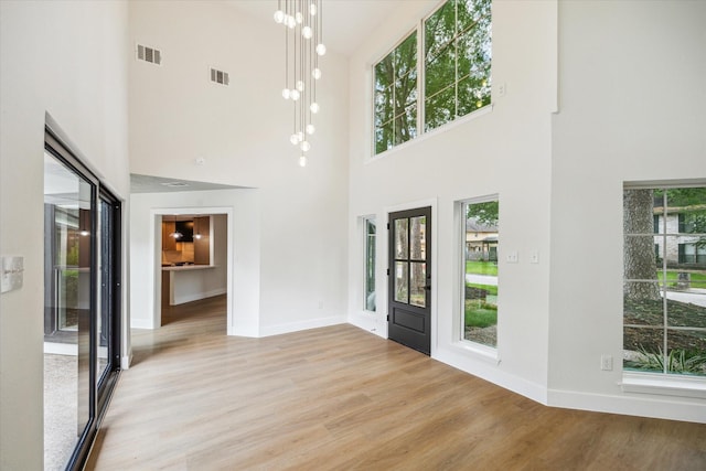 entrance foyer featuring visible vents, baseboards, a high ceiling, and wood finished floors