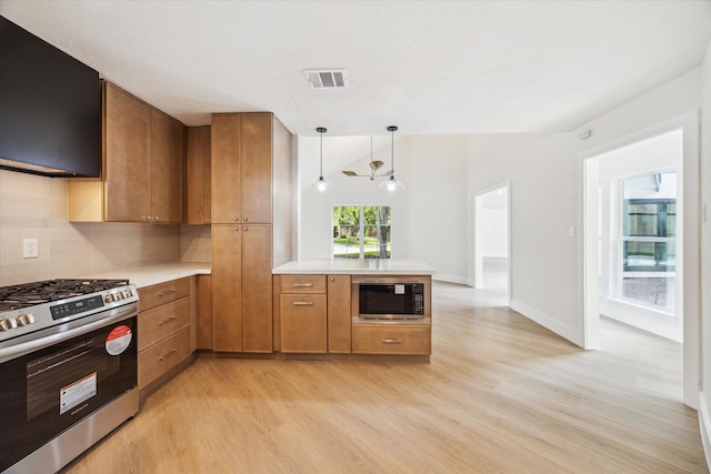 kitchen featuring brown cabinetry, visible vents, built in microwave, light wood-type flooring, and stainless steel gas range
