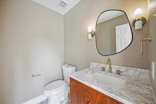 bathroom featuring visible vents, toilet, and vanity