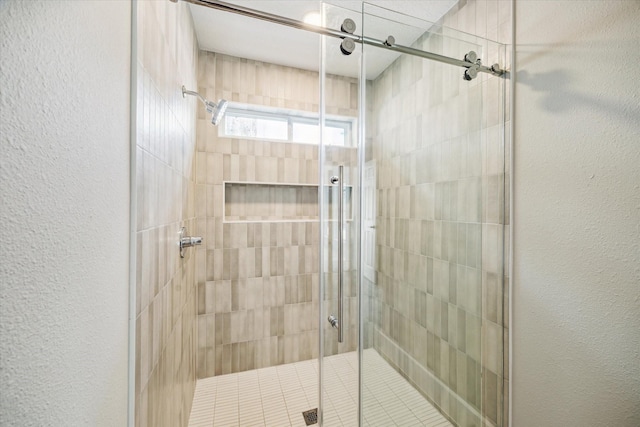 full bathroom with a textured wall and a stall shower