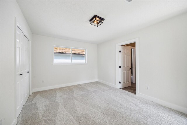 unfurnished bedroom with carpet floors, baseboards, and connected bathroom