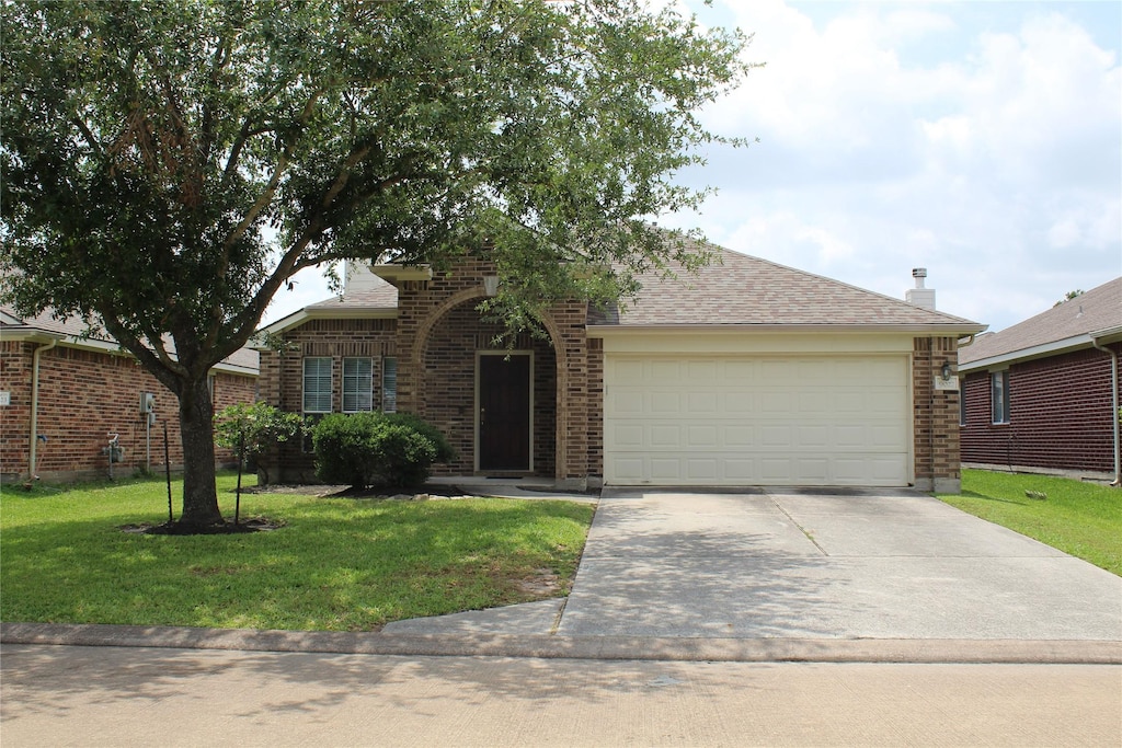 ranch-style house with a shingled roof, a front lawn, brick siding, a garage, and driveway