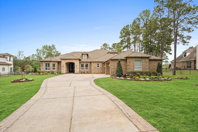 33026 Sawgrass Ct, Magnolia, TX 77354 - french country inspired facade featuring fence, curved driveway, a front lawn, and brick siding