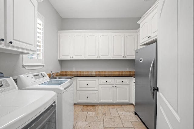 33026 Sawgrass Ct, Magnolia, TX 77354 - clothes washing area featuring separate washer and dryer, a sink, cabinet space, and stone tile flooring