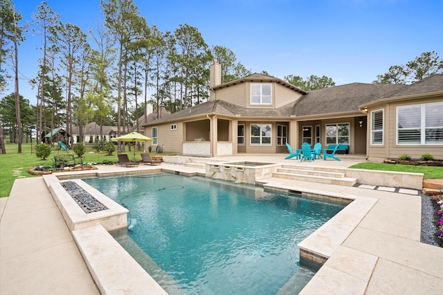 33026 Sawgrass Ct, Magnolia, TX 77354 - rear view of house with an in ground hot tub, a chimney, an outdoor pool, a patio area, and a playground