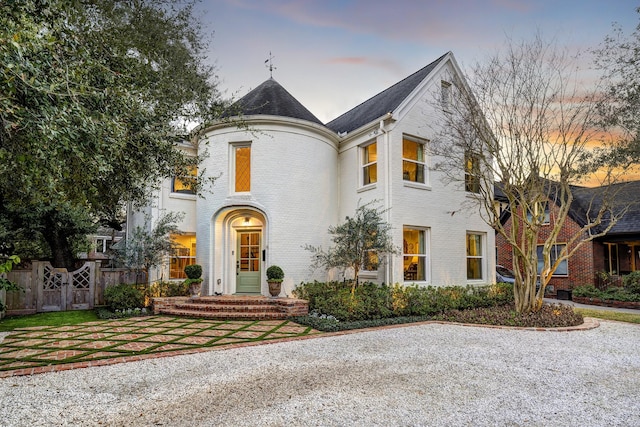 french country home with brick siding and fence