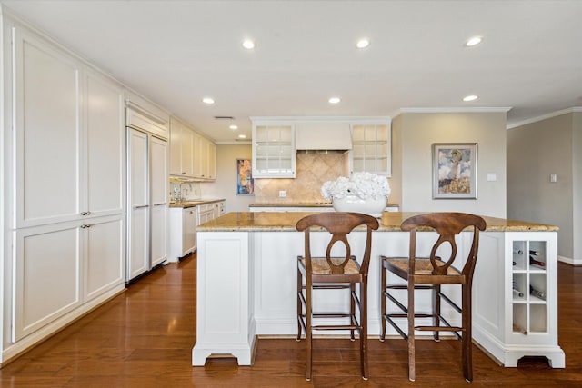 kitchen featuring decorative backsplash, paneled refrigerator, white dishwasher, a center island, and ornamental molding