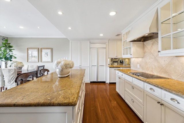 kitchen with a kitchen island, black electric cooktop, light stone counters, custom exhaust hood, and dark wood-type flooring