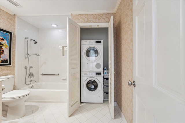 bathroom featuring stacked washer / dryer, tile patterned floors, toilet,  shower combination, and wallpapered walls