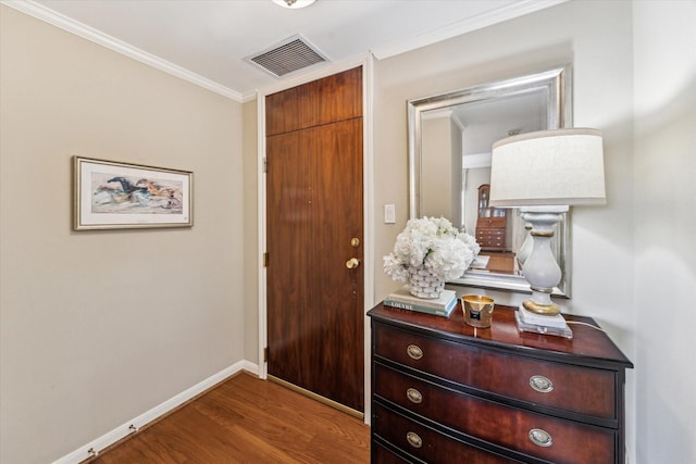 entryway featuring visible vents, ornamental molding, baseboards, and wood finished floors