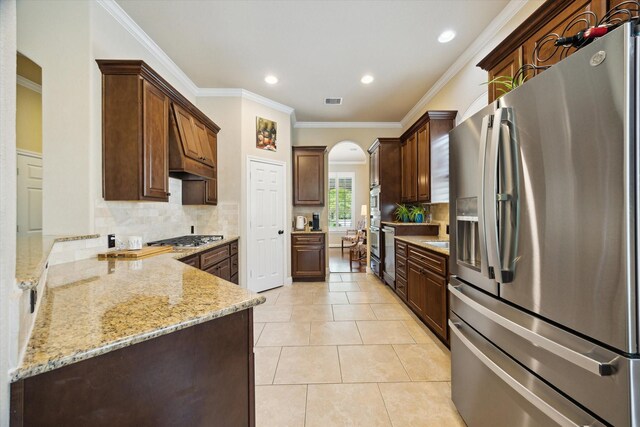kitchen featuring light stone counters, arched walkways, backsplash, and stainless steel appliances