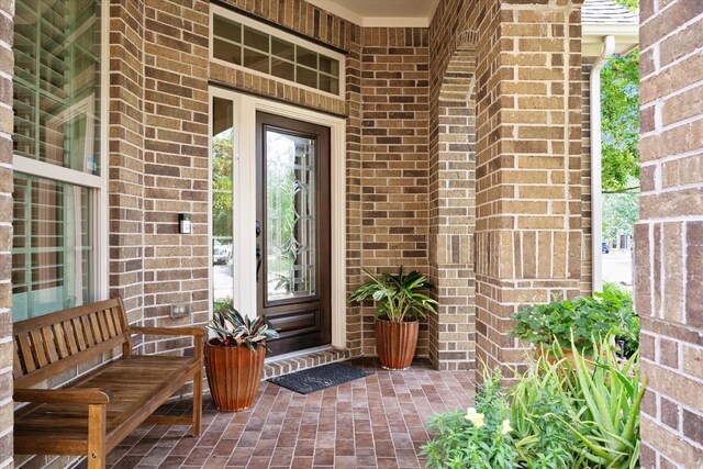 property entrance with covered porch and brick siding
