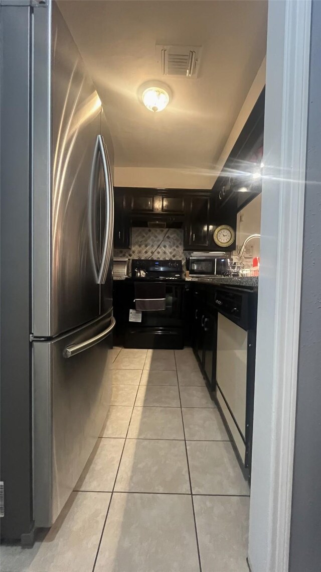 kitchen with light tile patterned flooring, appliances with stainless steel finishes, dark cabinetry, backsplash, and visible vents