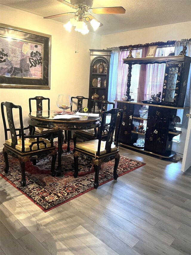 dining room with a ceiling fan, a textured ceiling, and wood finished floors