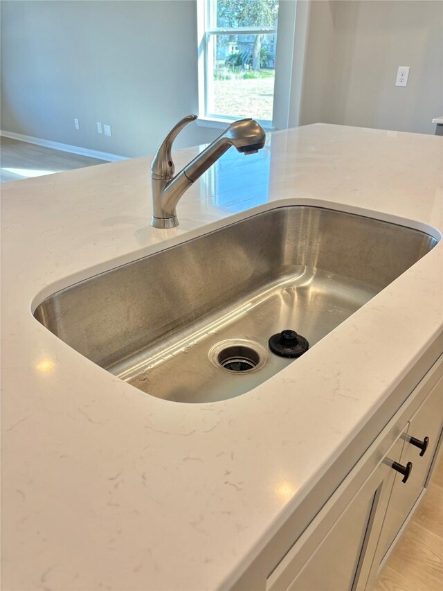 details with white cabinets, light stone countertops, and a sink