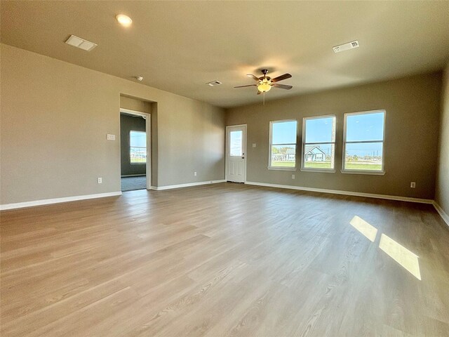interior space with baseboards, a ceiling fan, wood finished floors, and visible vents