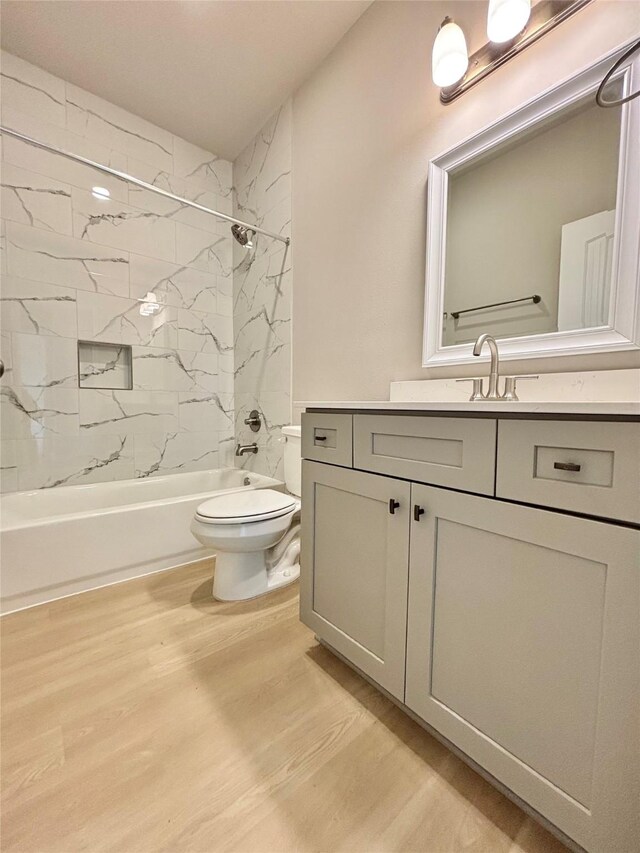 full bathroom featuring vanity, washtub / shower combination, wood finished floors, and toilet