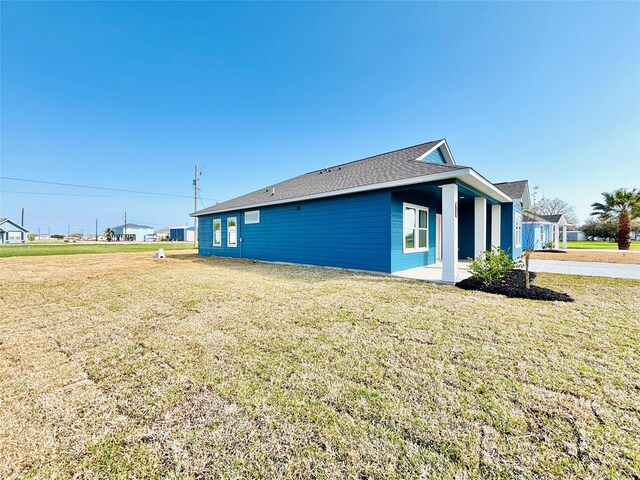 view of side of home with a lawn and roof with shingles