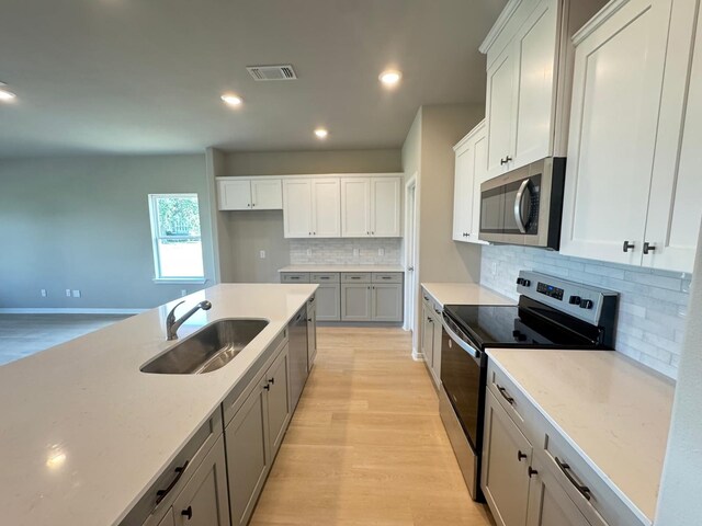 kitchen featuring stainless steel appliances, visible vents, a sink, and light wood-type flooring