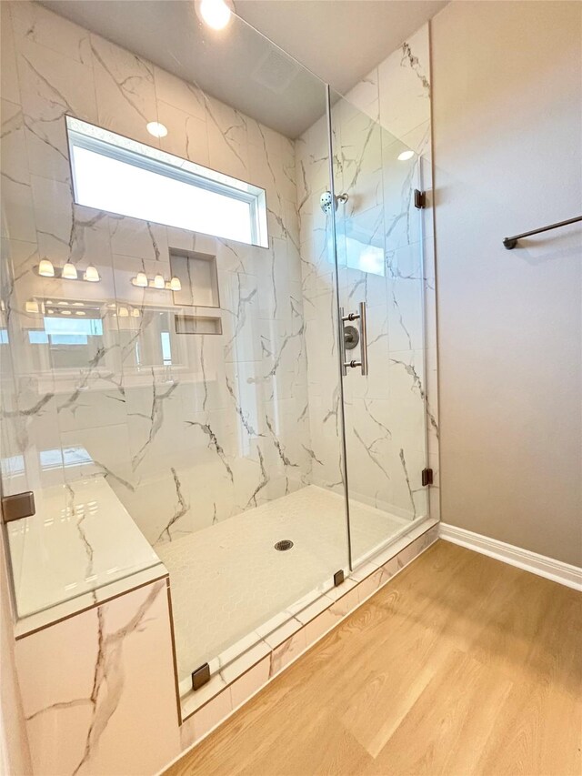 full bathroom featuring baseboards, a marble finish shower, and wood finished floors