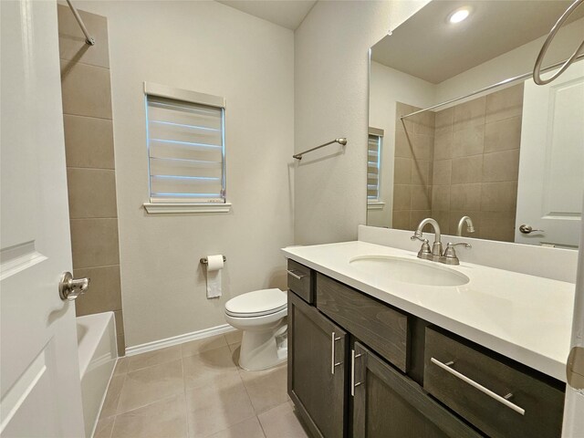 bathroom featuring vanity, toilet, baseboards, tile patterned floors, and shower / bath combination