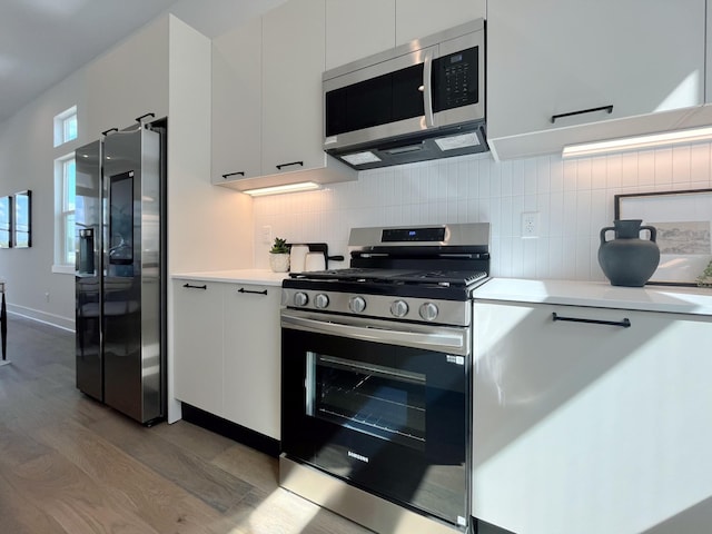 kitchen with light countertops, white cabinetry, wood finished floors, and stainless steel appliances