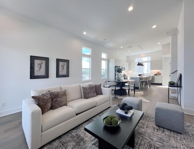 living area with light wood-style floors, baseboards, and recessed lighting