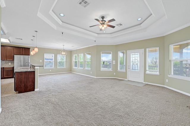 1004 8th St, San Leon, TX 77539 - unfurnished living room featuring visible vents, a raised ceiling, ornamental molding, and ceiling fan with notable chandelier