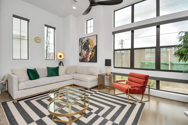 living room featuring wood finished floors, a towering ceiling, and ceiling fan