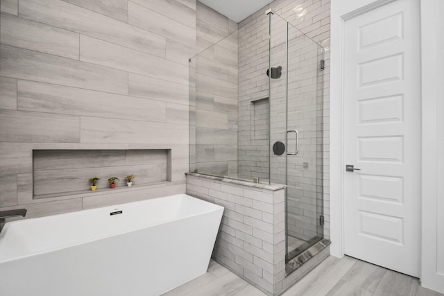 bathroom featuring a shower stall and a soaking tub
