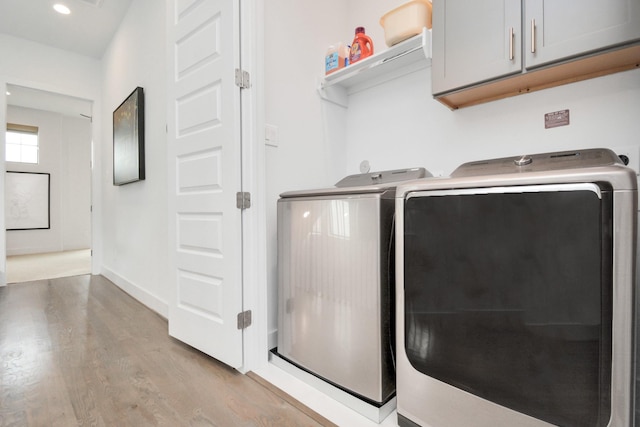 washroom featuring cabinet space, washer and dryer, light wood finished floors, recessed lighting, and baseboards
