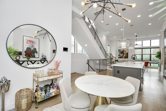 dining room featuring wood finished floors, a chandelier, plenty of natural light, stairs, and recessed lighting