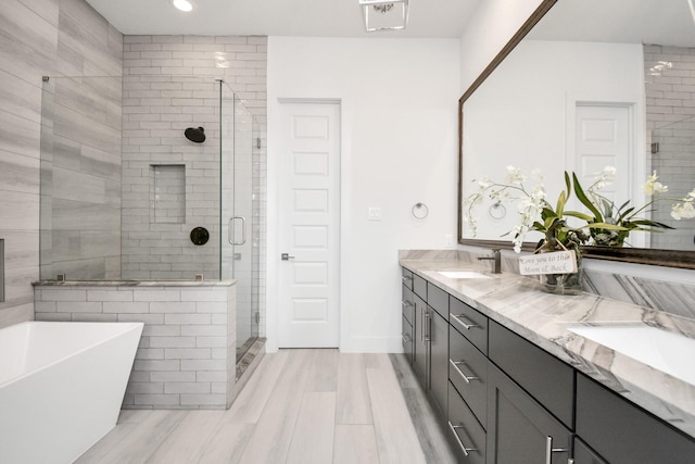 bathroom featuring a shower stall, double vanity, a soaking tub, recessed lighting, and baseboards